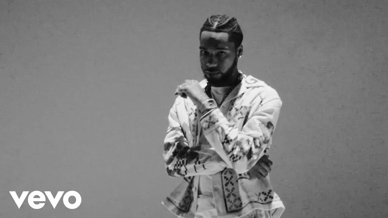 Key Glock in a light patterned suit looks at his wrist in a black-and-white image